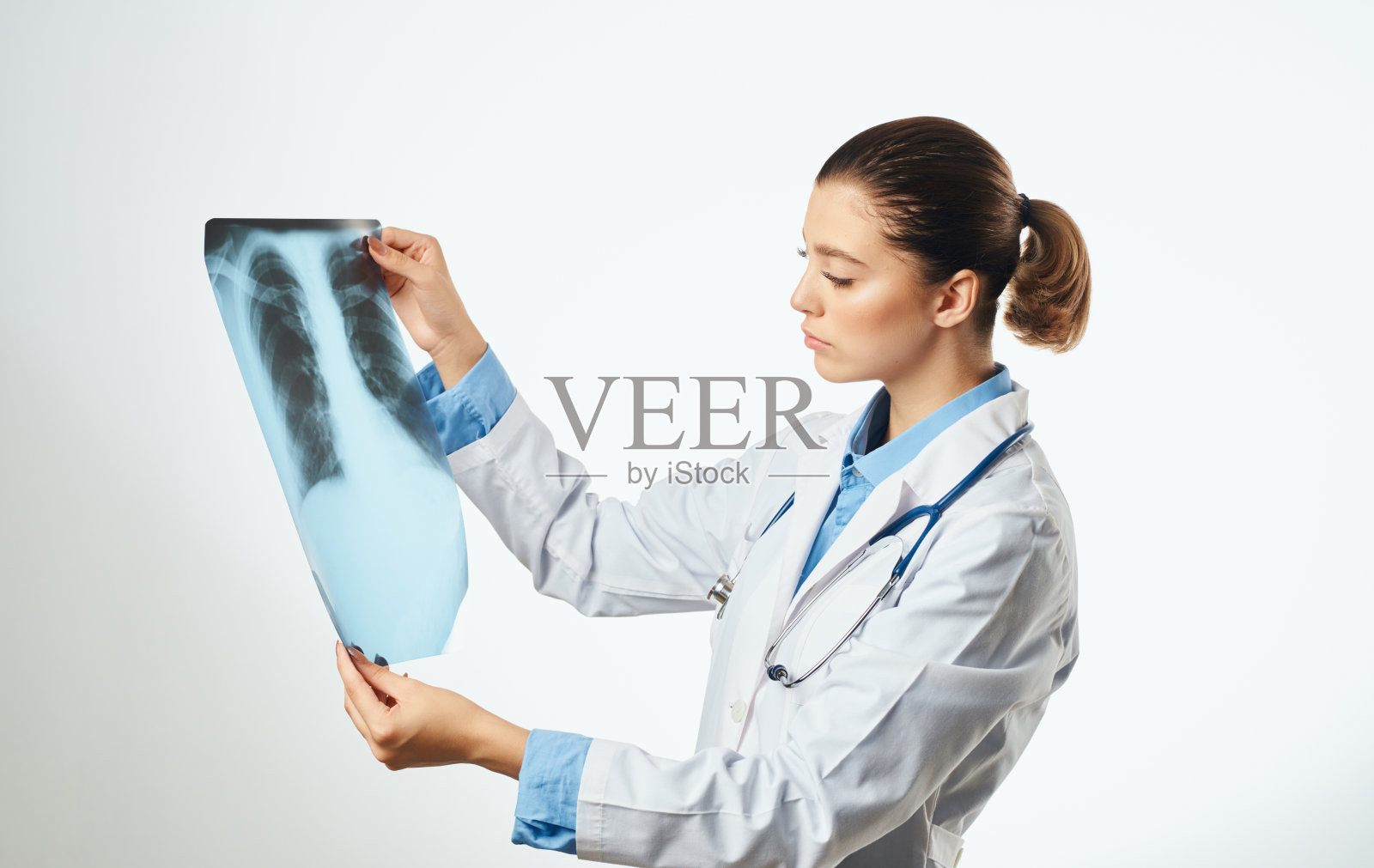 女医生用听诊器检查x光片和医用长袍眼镜照片摄影图片