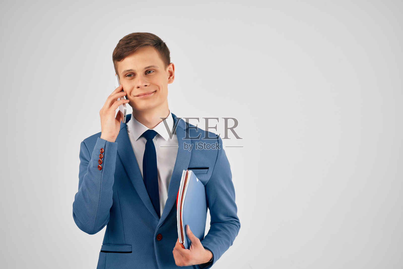 西装革履的蓝色文件夹男子在电话里讲着专业的工作照片摄影图片