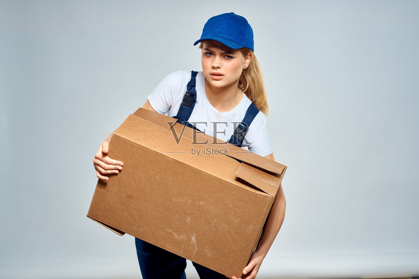 一个穿着工作服的女人手里拿着一个盒子，一个送餐员照片摄影图片