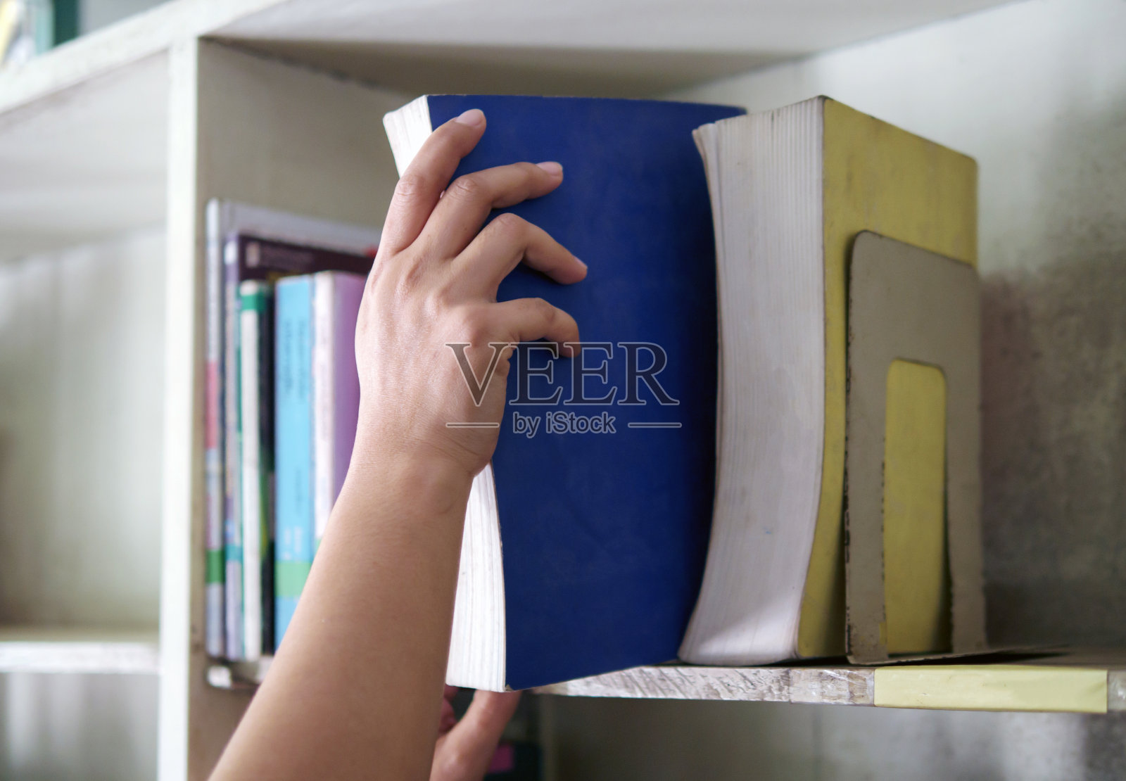 一个女人从书架上拿出一本书的手照片摄影图片