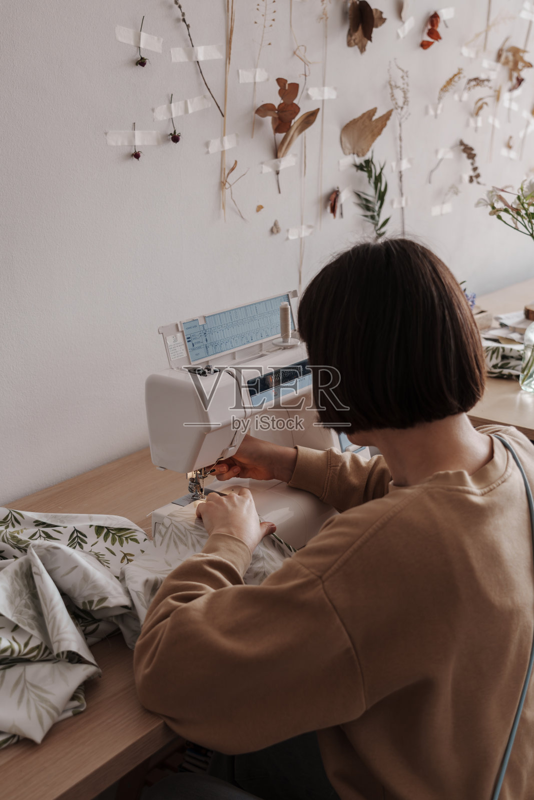 在阳光明媚的车间里，富有创造力的妇女在机器上缝纫照片摄影图片