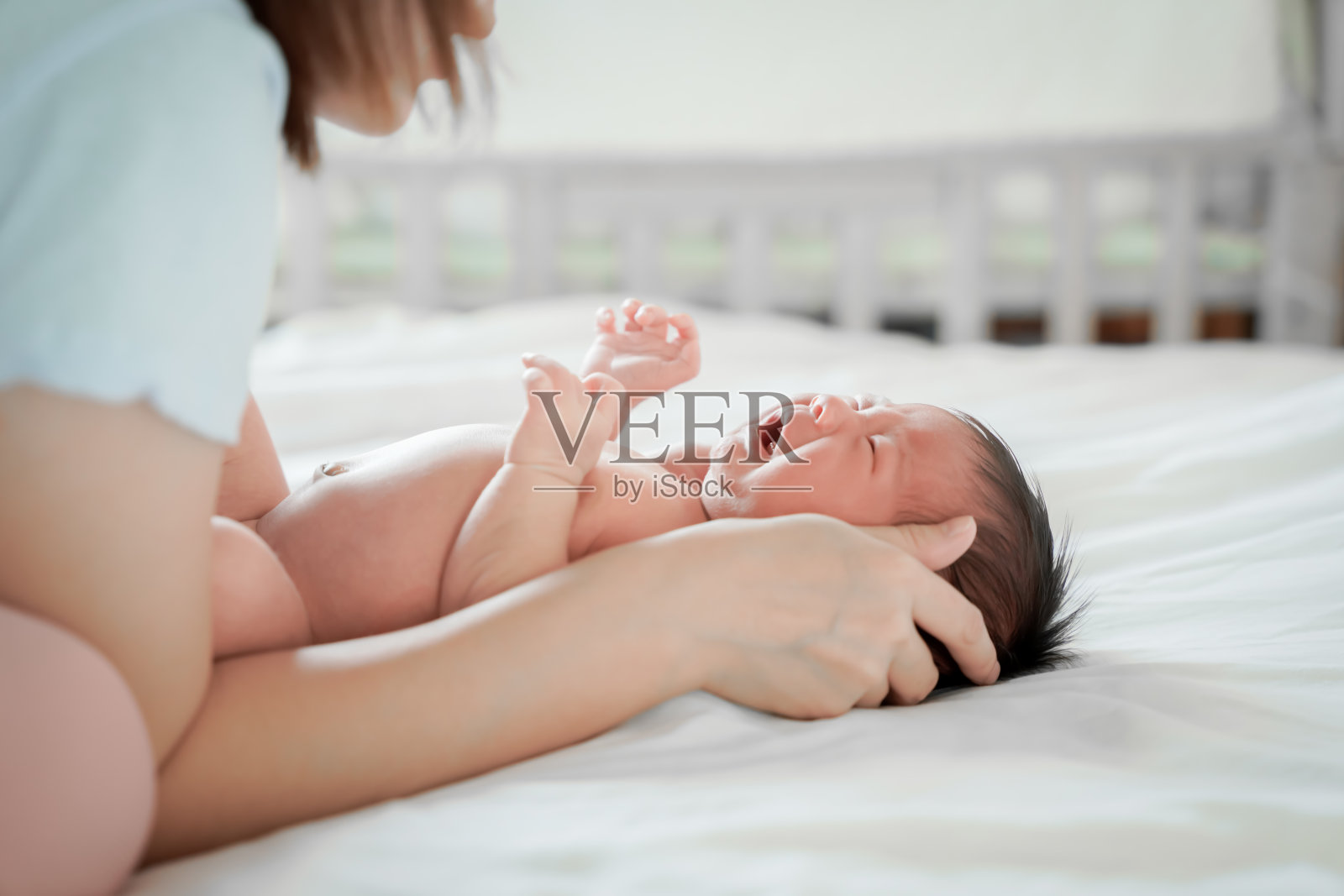 新生儿是亚裔躺在卧室白色的床上我哭了。照片摄影图片