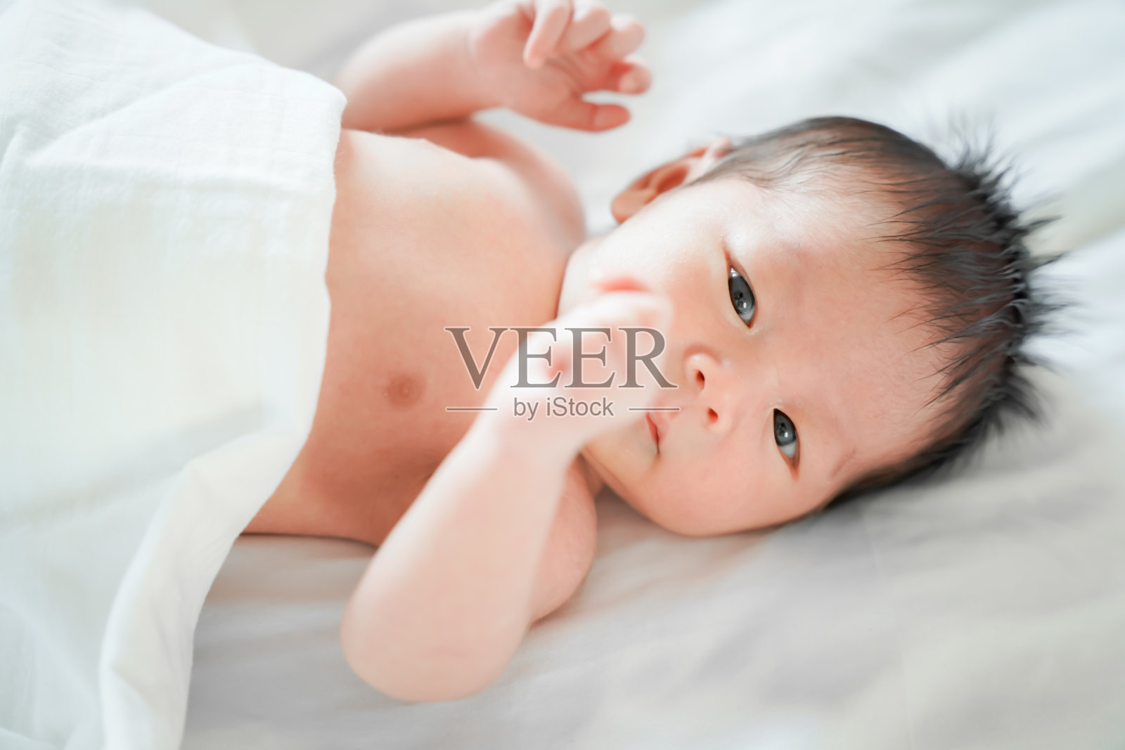 刚出生的男婴是一个亚裔的人躺在卧室白色的床上照片摄影图片