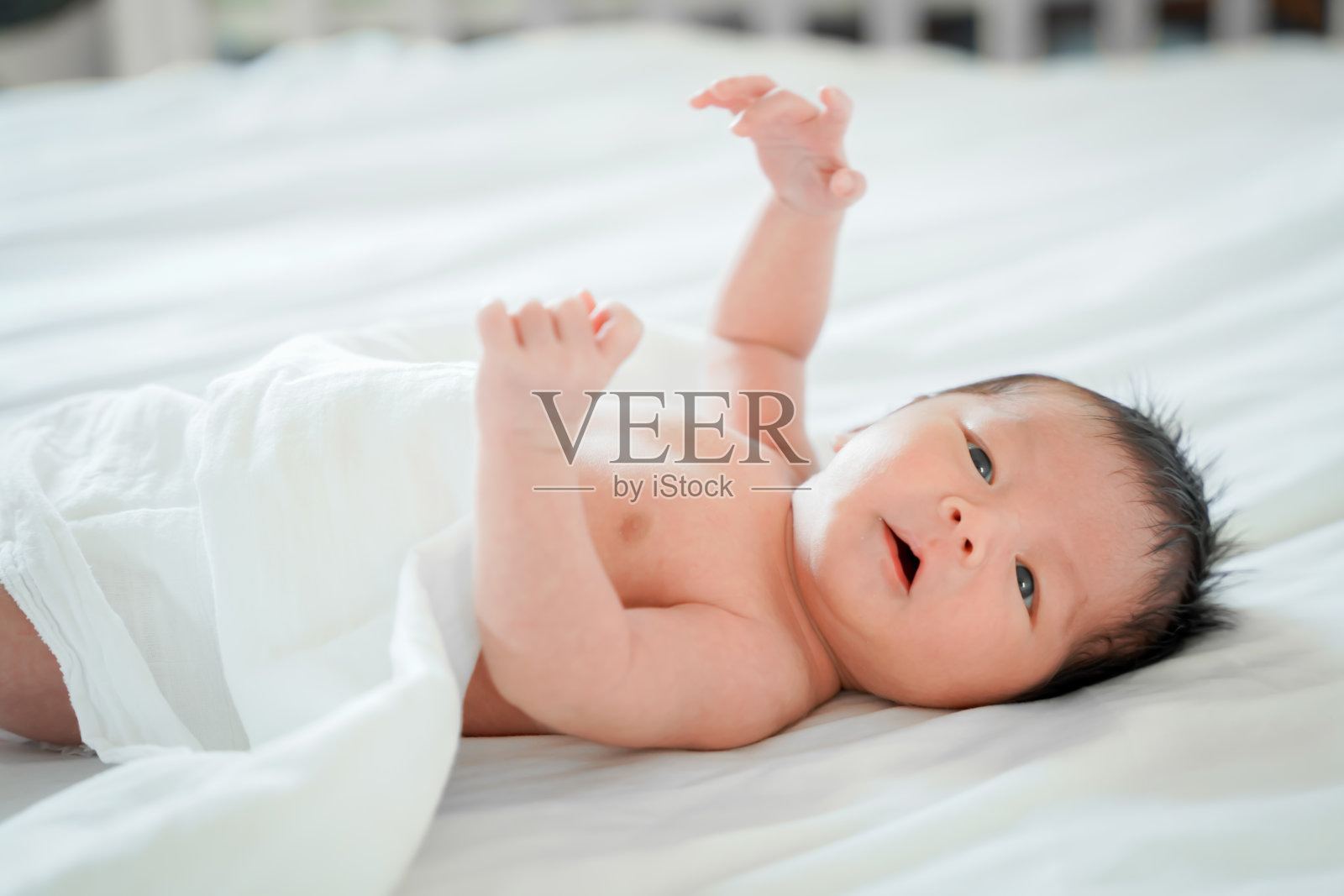 刚出生的男婴是一个亚裔的人躺在卧室白色的床上照片摄影图片