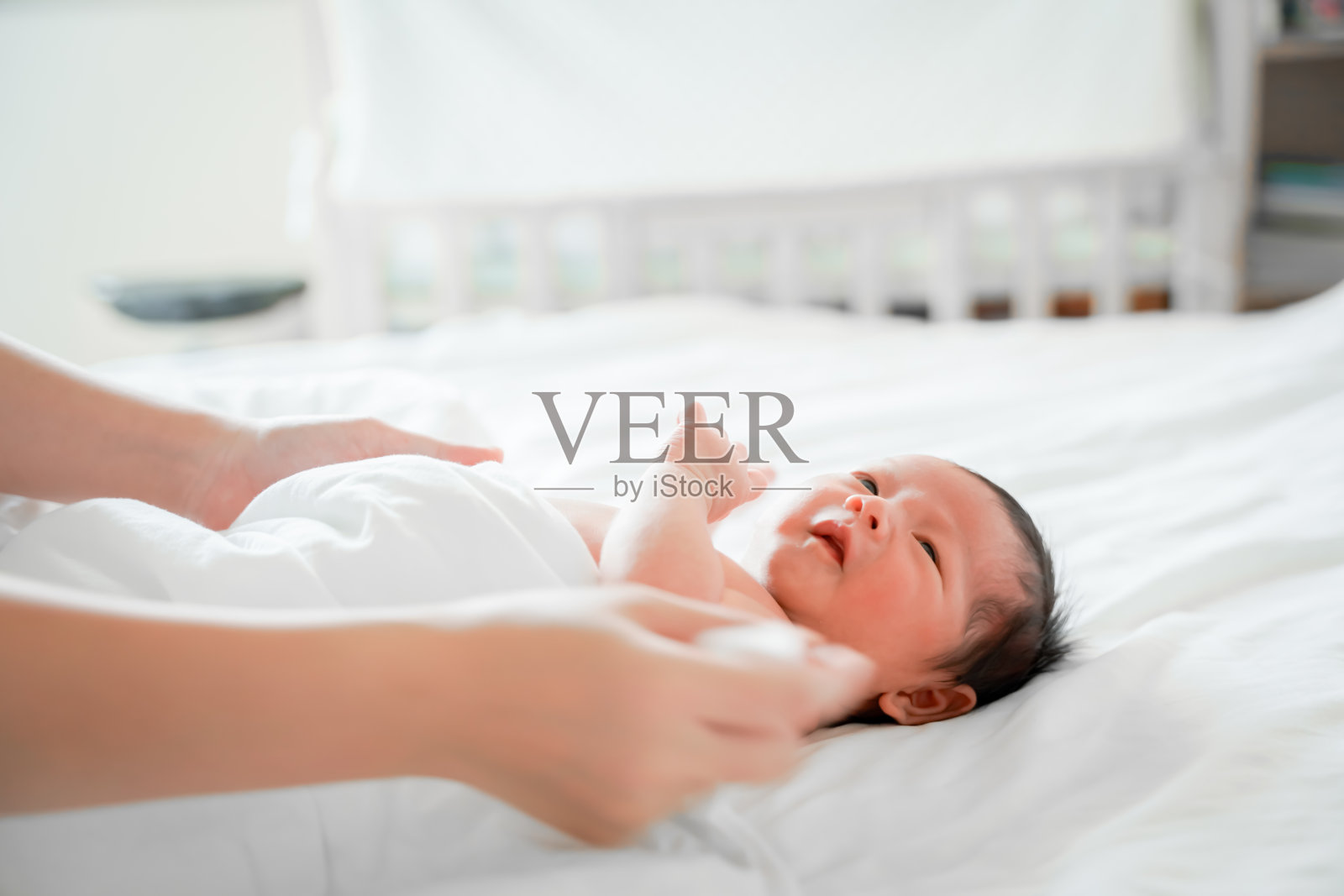刚出生的男婴是一个亚裔的人躺在卧室白色的床上照片摄影图片