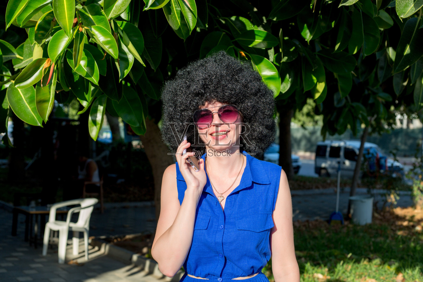 可爱苗条的黑发女人，穿着蓝裙子，手里拿着电话照片摄影图片