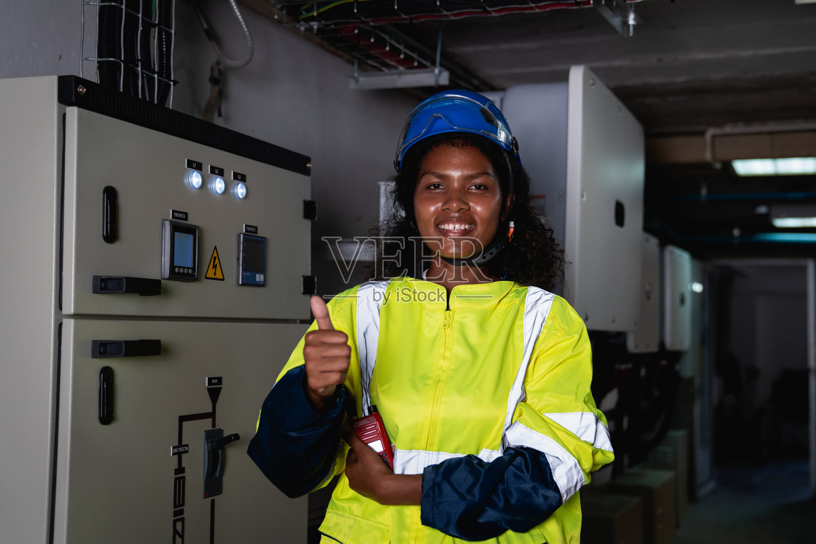 身穿黄蓝相间安全背心的技术人员拿着对讲机微笑着照片摄影图片