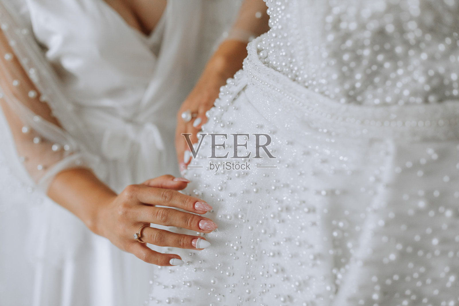 白色婚纱在房间里的人体模型上，新娘的手在人体模型上的特写。婚礼细节，现代婚纱有长裙摆，长袖和开背照片摄影图片