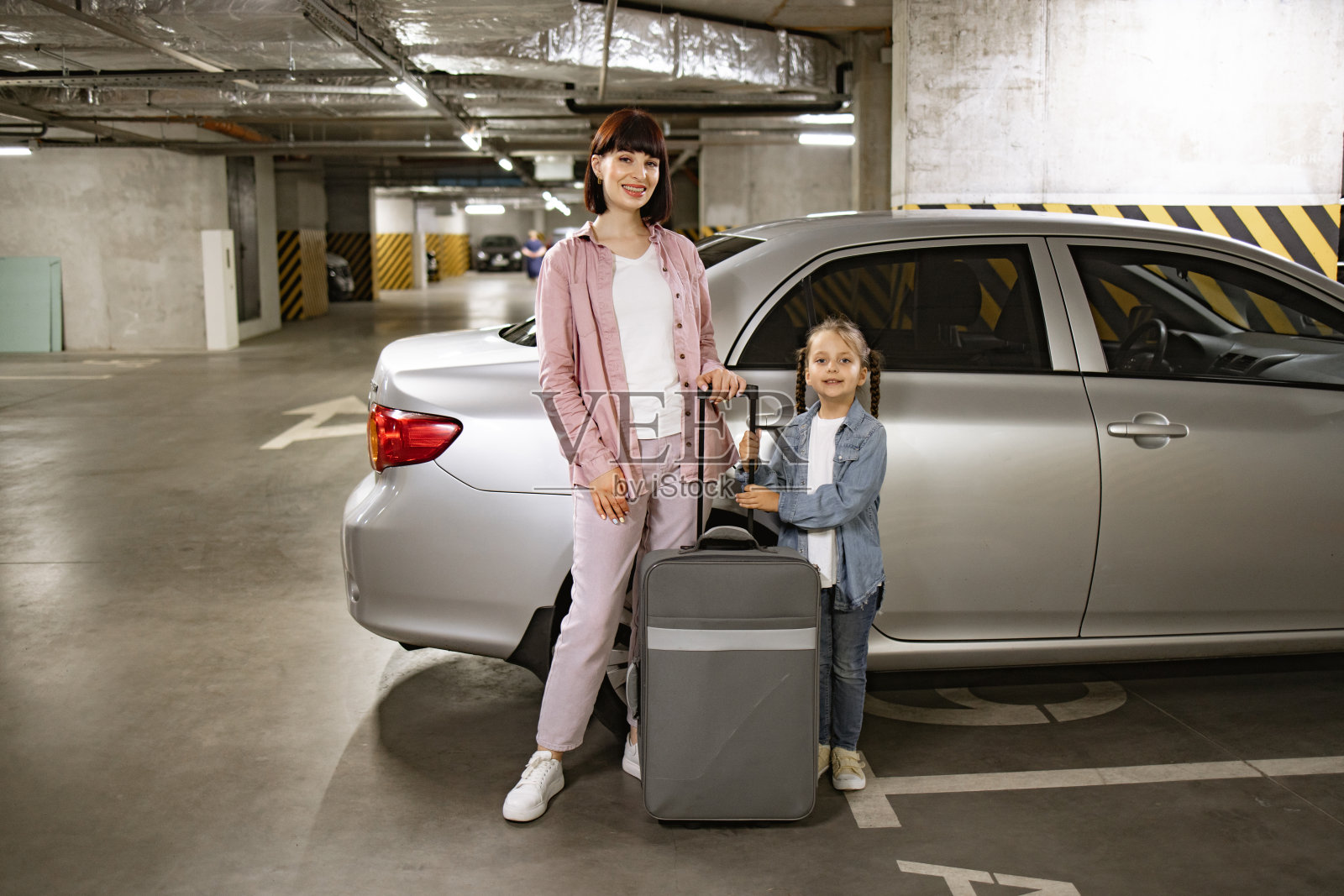 白人母女，站在地下停车场的汽车旁。照片摄影图片