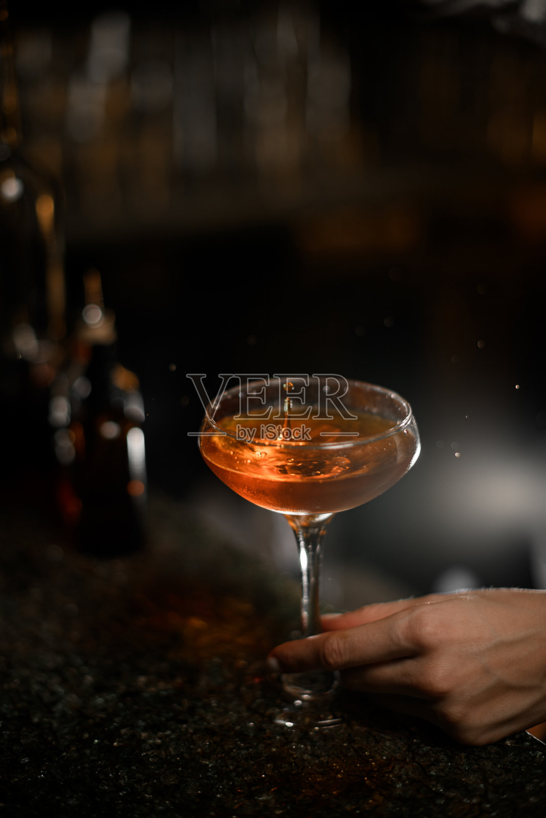 女性的手拿着鸡尾酒杯，杯中有鸡尾酒照片摄影图片