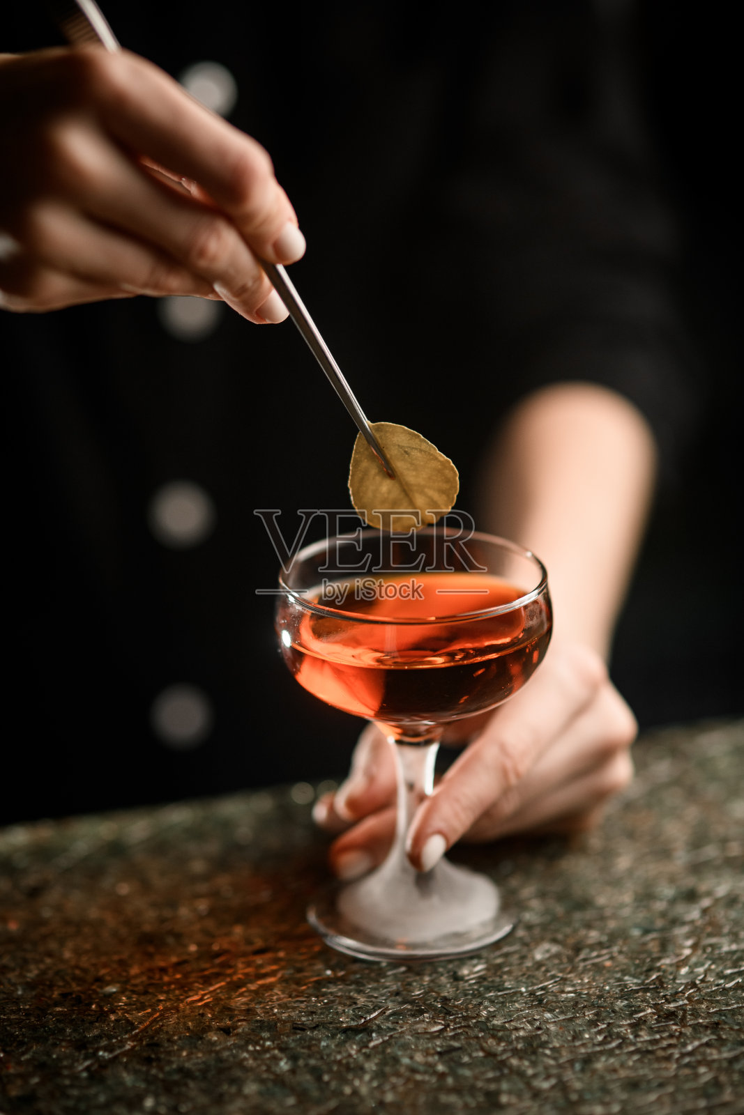 女性的手在鸡尾酒中加入一片绿叶照片摄影图片