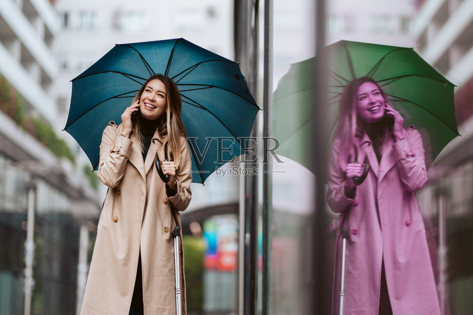 一个漂亮的年轻女子站在伞下讲电话。照片摄影图片