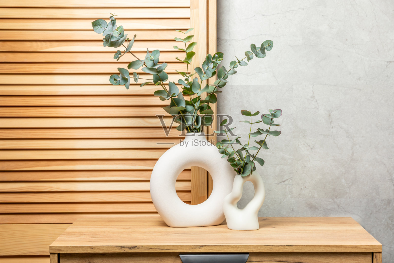 一个花瓶里的绿色桉树叶子立在一个抽屉柜上，背景是墙。芳香疗法。美丽的桉树花束。极简主义的室内装饰有鲜花、蜡烛和芳香扩散器。照片摄影图片