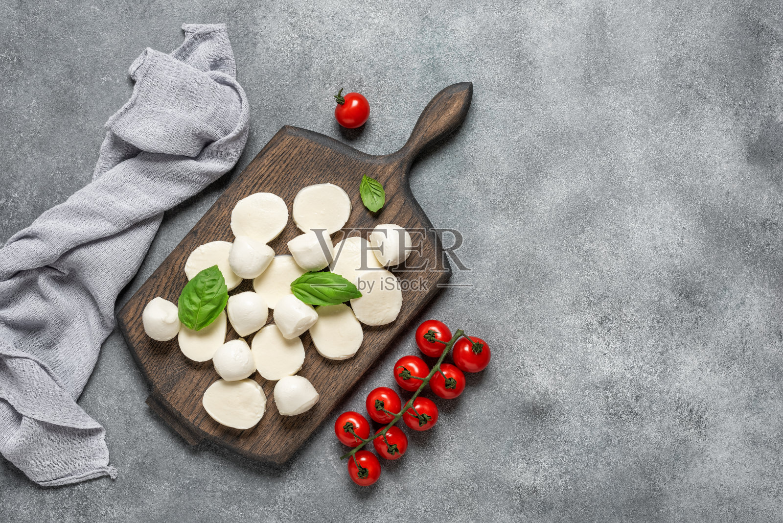 灰色背景的马苏里拉奶酪配罗勒叶和圣女番茄。俯视图，平面布局，复制空间。照片摄影图片