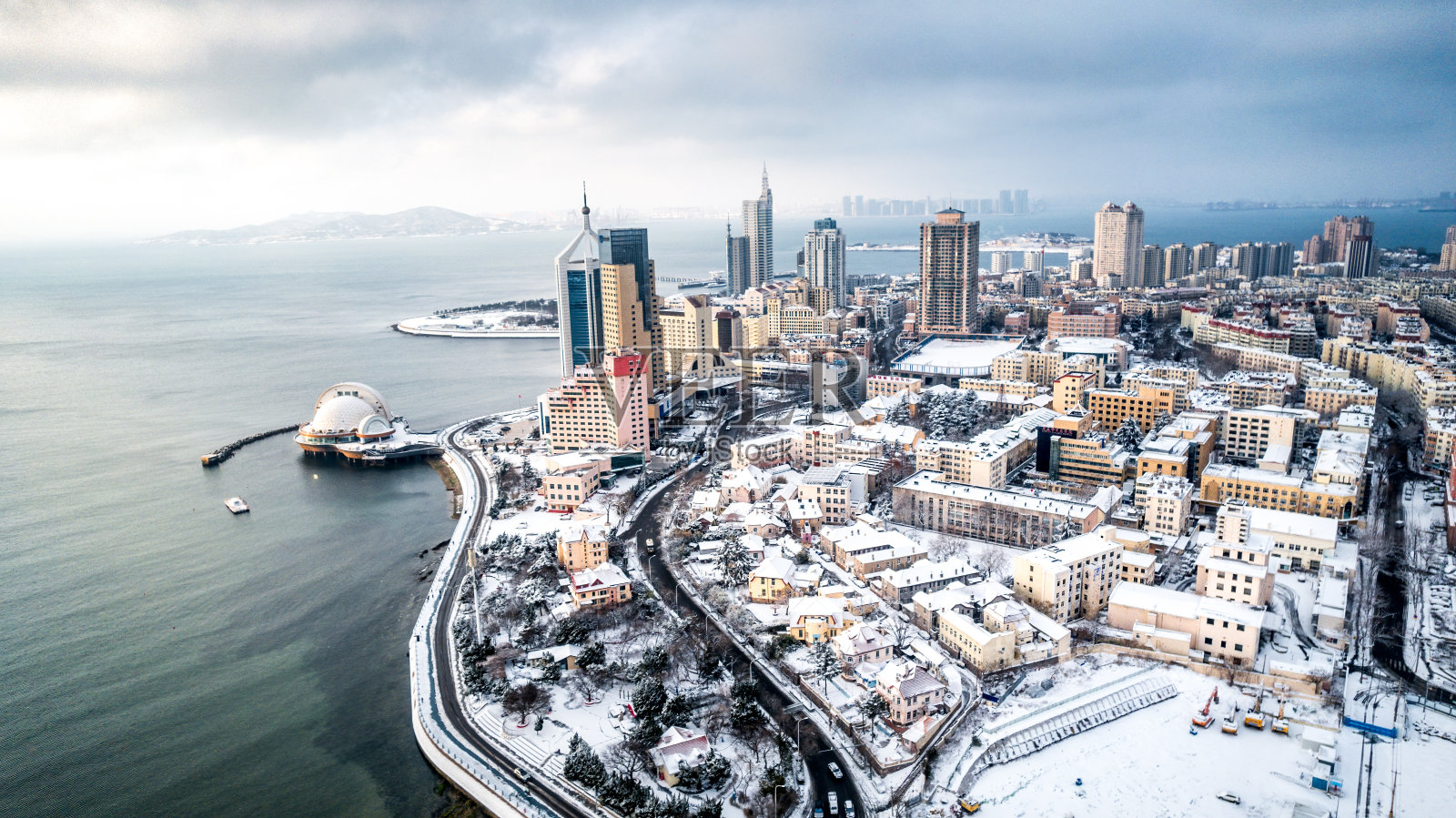在寒冷的冬日，航拍的中国山东省青岛市一个下雪的城市照片摄影图片