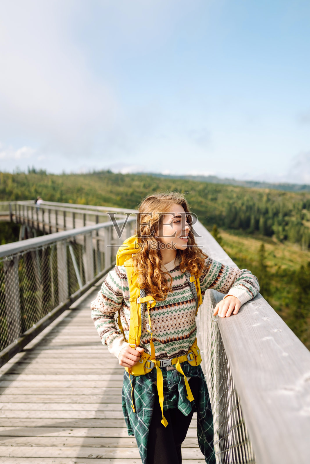 年轻女子站在自然背景的木桥上。照片摄影图片