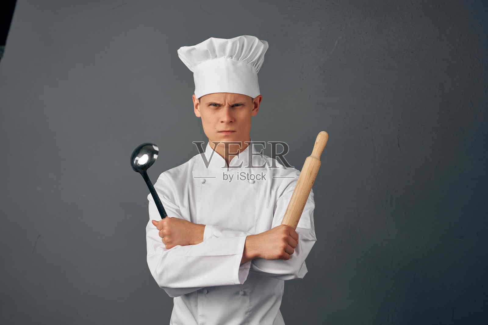 一个穿着厨师制服的人，手里拿着勺子在做饭照片摄影图片