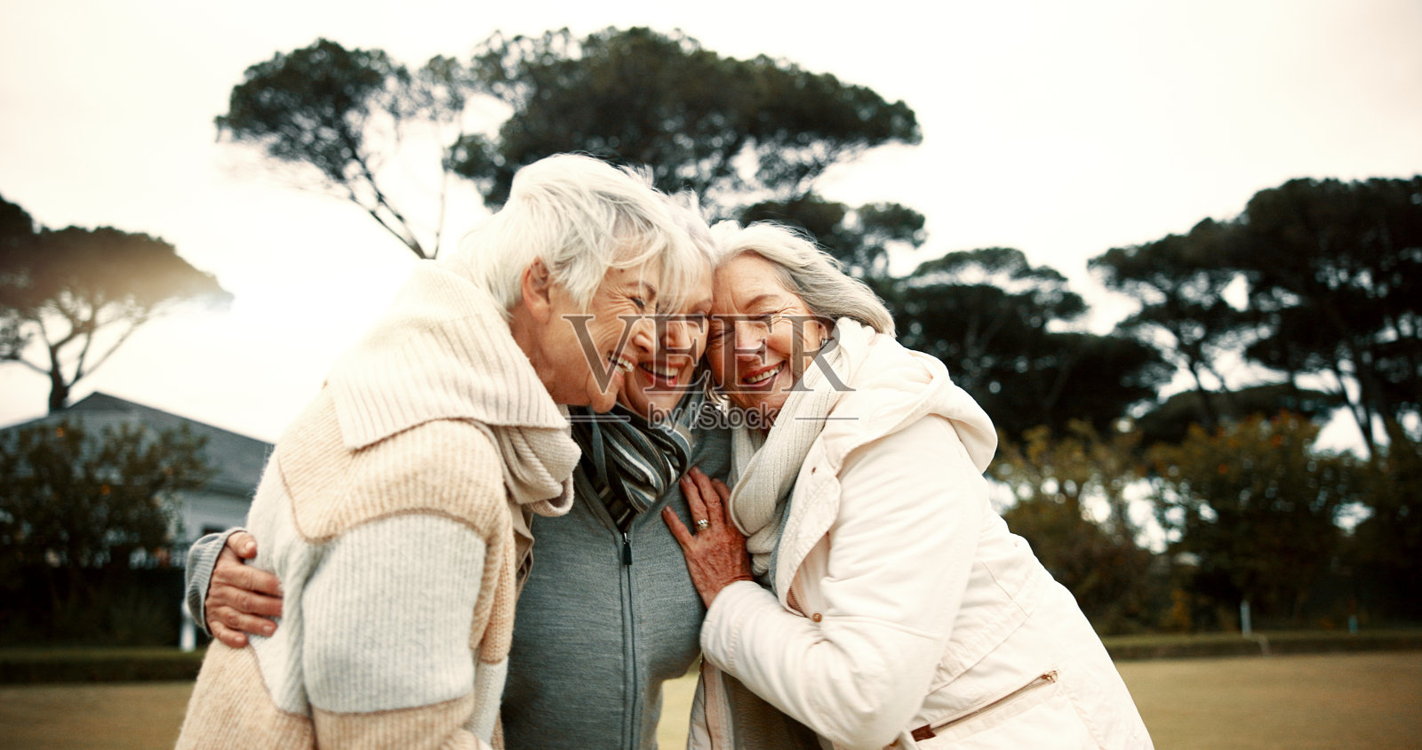 退休后，在公园里和年长的女性朋友一起谈笑风生。快乐，微笑和有趣与一群老年人在花园拥抱幽默或乐趣照片摄影图片
