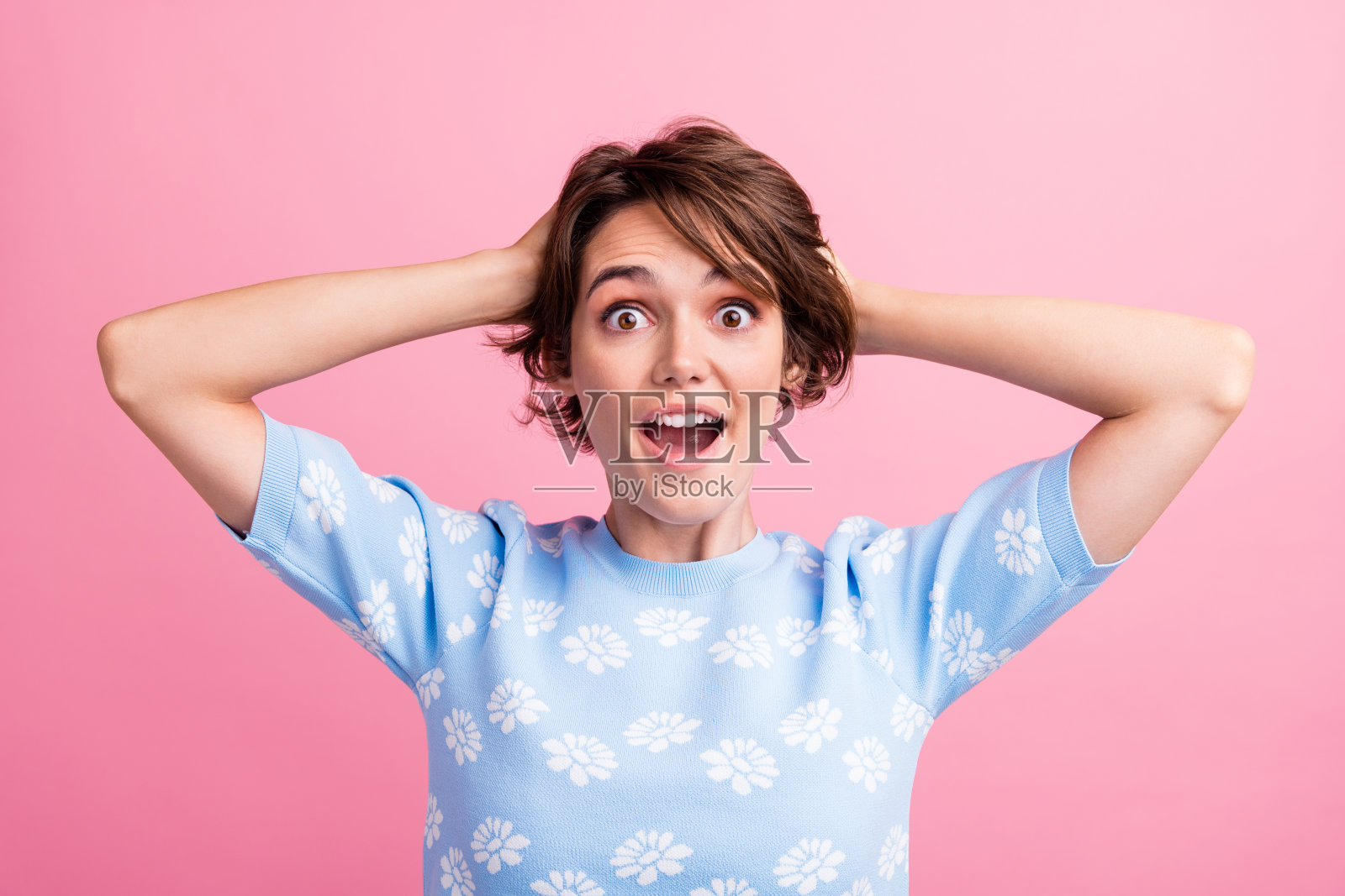 惊讶的漂亮女孩的肖像手摸头张开嘴不能相信孤立在粉红色的背景照片摄影图片