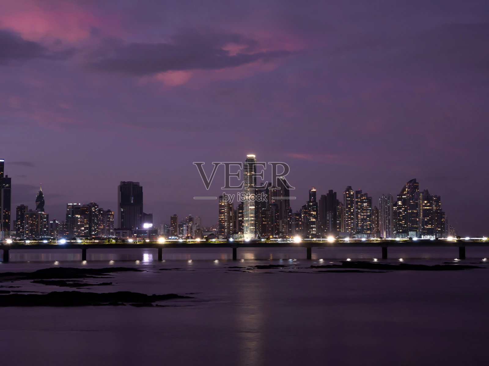 黎明时分，美丽的紫色天空笼罩在灯火通明的现代城区上空照片摄影图片