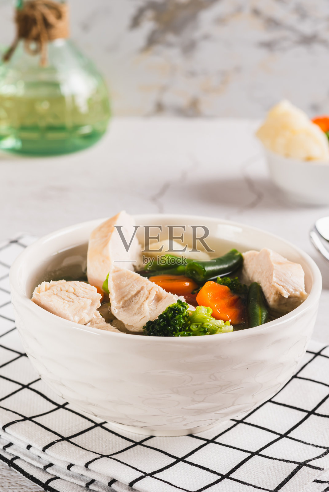 用鸡肉、花椰菜、西兰花、胡萝卜和四季豆在碗里做成的自制汤照片摄影图片