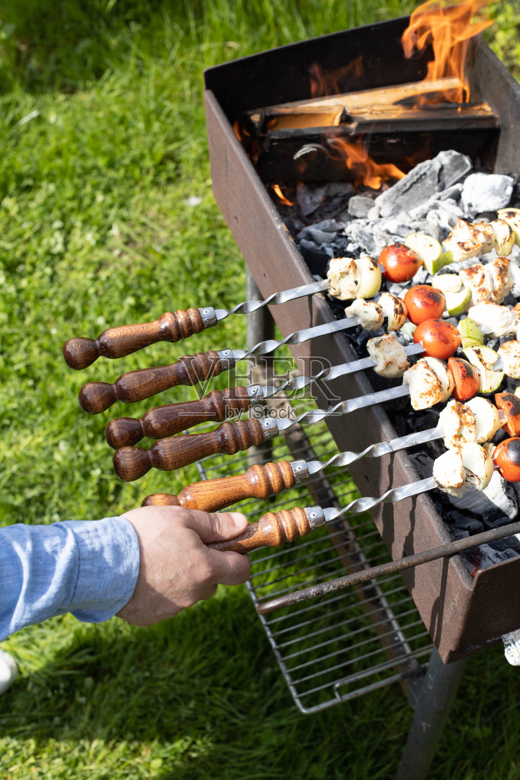 烤肉串或羊肉串，在烧烤架上用燃烧的木炭烤蔬菜。把猪肉串在金属串上烤。照片摄影图片