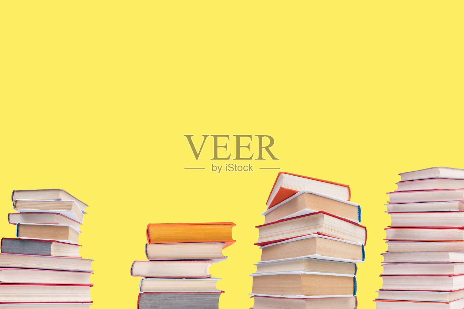 木制甲板桌和黄色背景上的精装书组成。书堆积。回到学校。副本的空间。教育背景。照片摄影图片