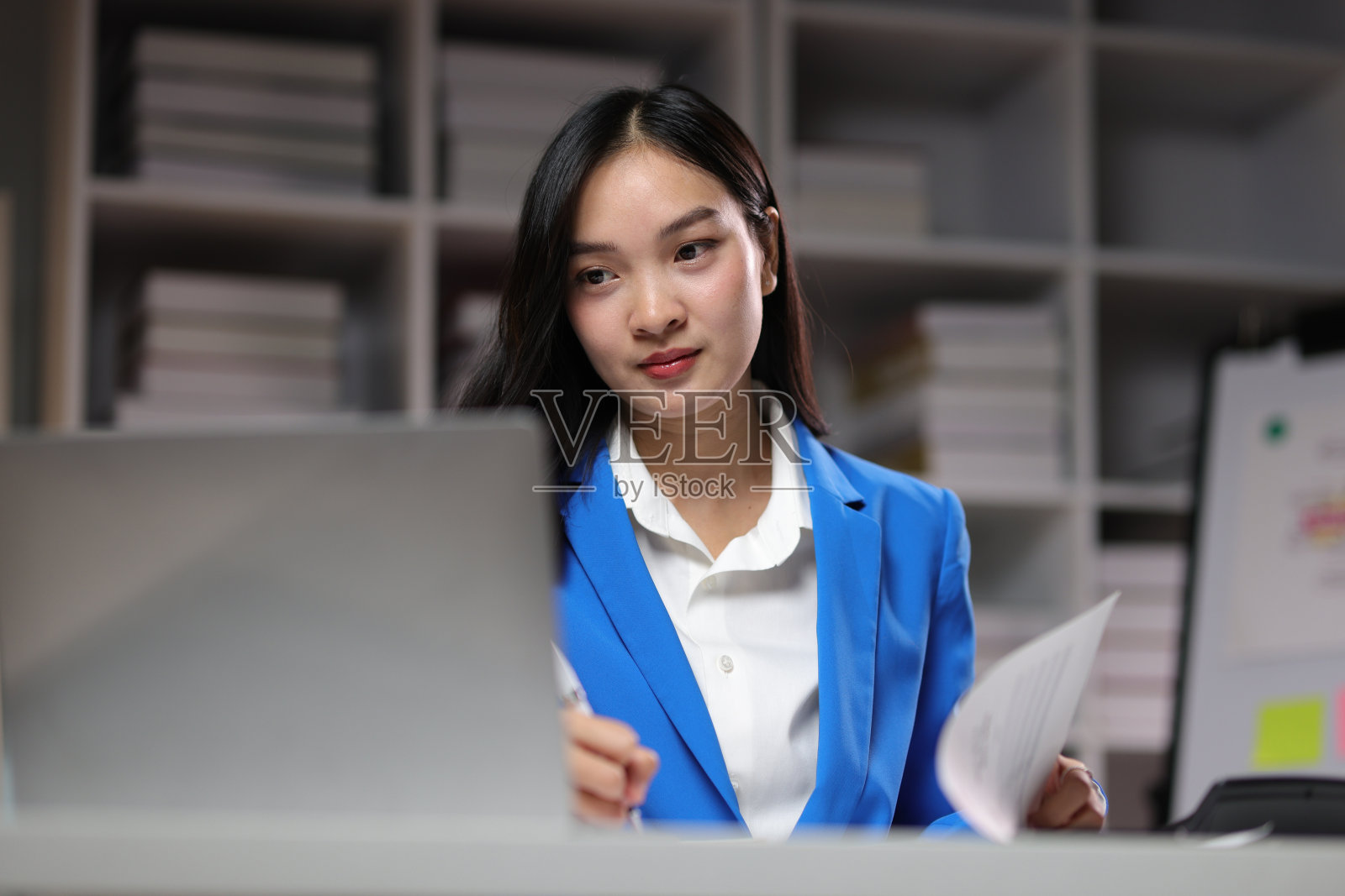 压力和疲劳的亚洲年轻女商人晚上在办公室加班时感到头痛。照片摄影图片