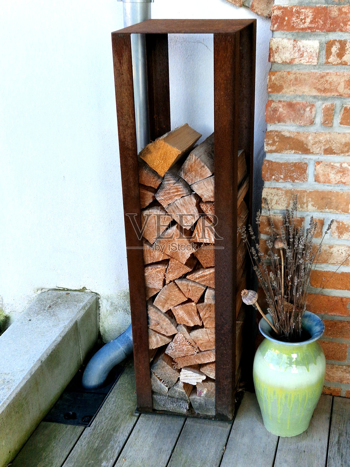 一个笼子形状的盒子，边缘是生锈的钢，矗立在房子的木板露台上。在壁炉、烤架或披萨烤箱中加热。由铁匠定做的名牌产品照片摄影图片