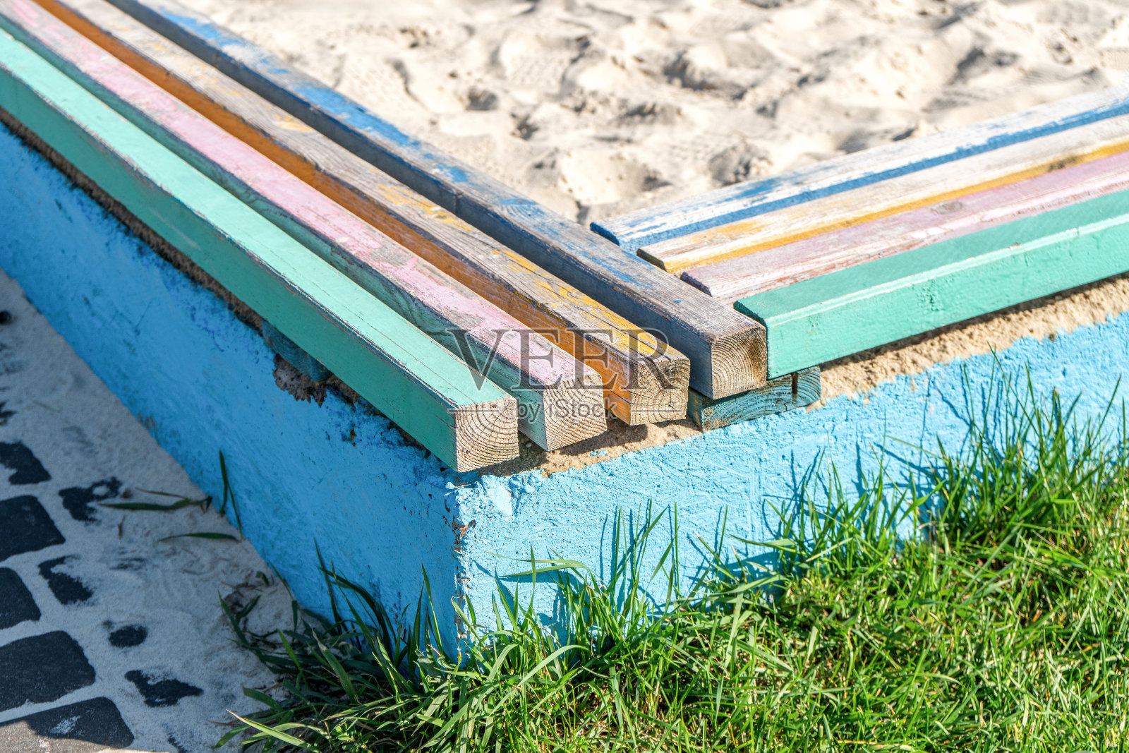 混凝土屏障与彩色木条作为座位，围绕着一个儿童沙坑照片摄影图片