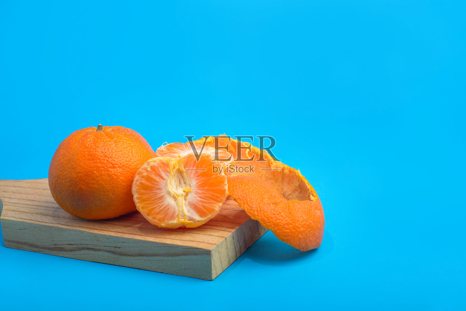 有皮的橘子和蓝色背景的去皮橘子。照片摄影图片