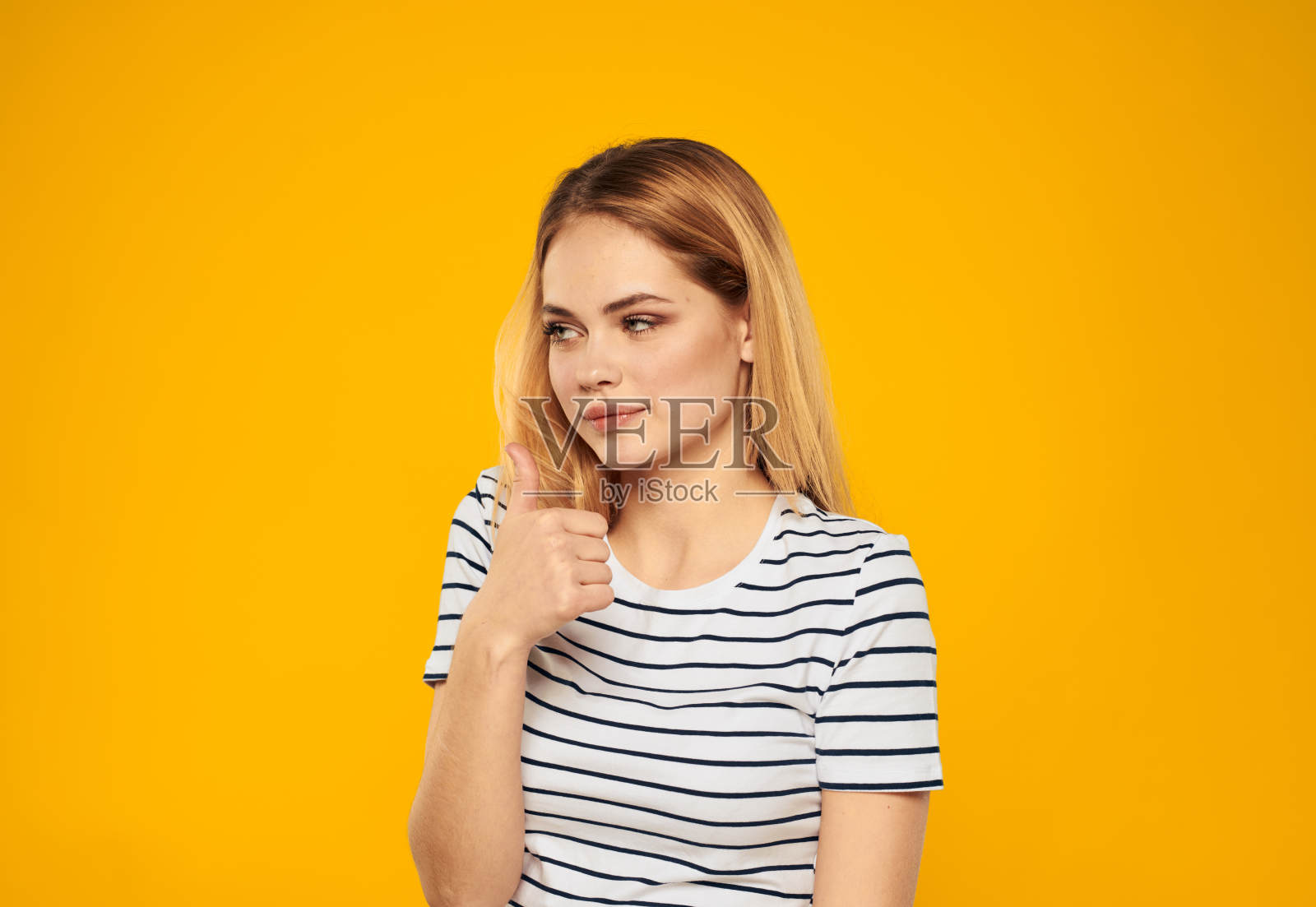 情绪化的女人在黄色背景上穿着条纹t恤的肖像照片摄影图片