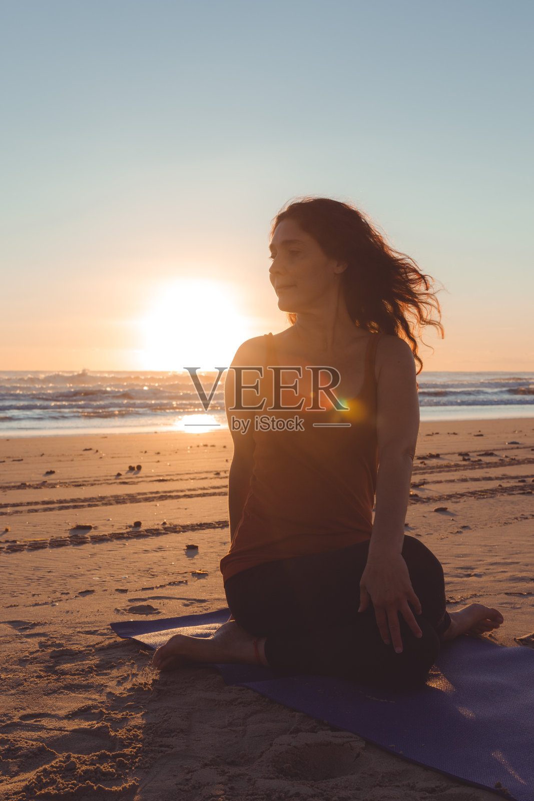 一个女人在日落时分在海滩上做伸展运动的剪影照片摄影图片