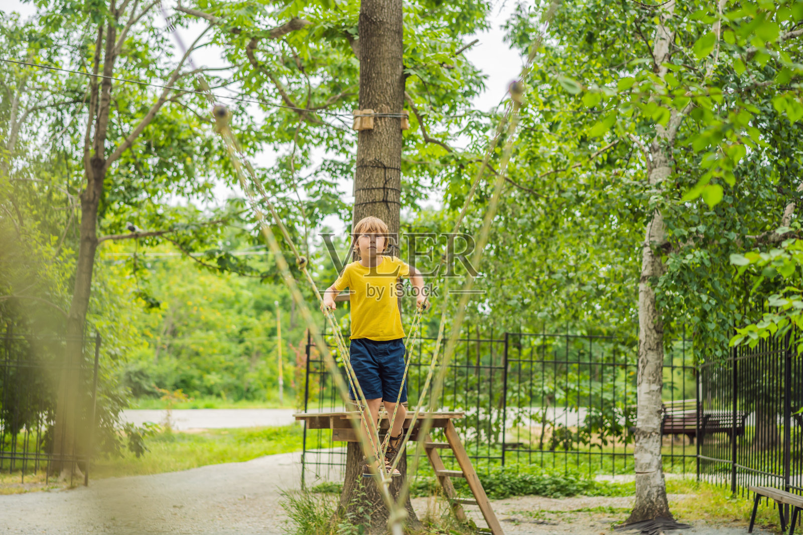 绳子公园里的小男孩。孩子们在公园的新鲜空气中积极地进行体力活动。儿童培训照片摄影图片