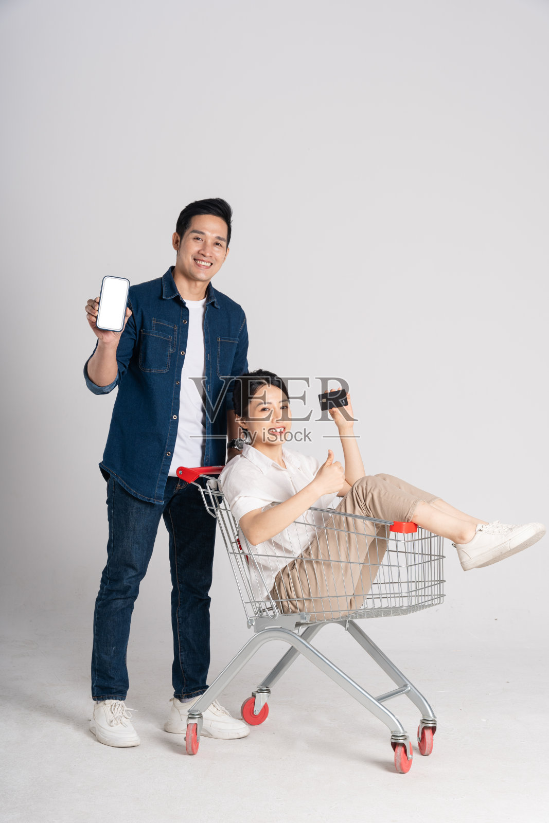 幸福微笑的夫妇推着超市推车，孤立在白色背景上照片摄影图片