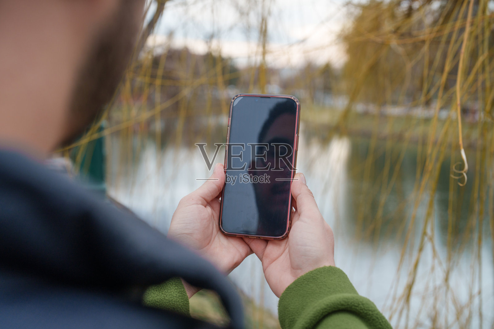 靠近河边使用手机的手照片摄影图片