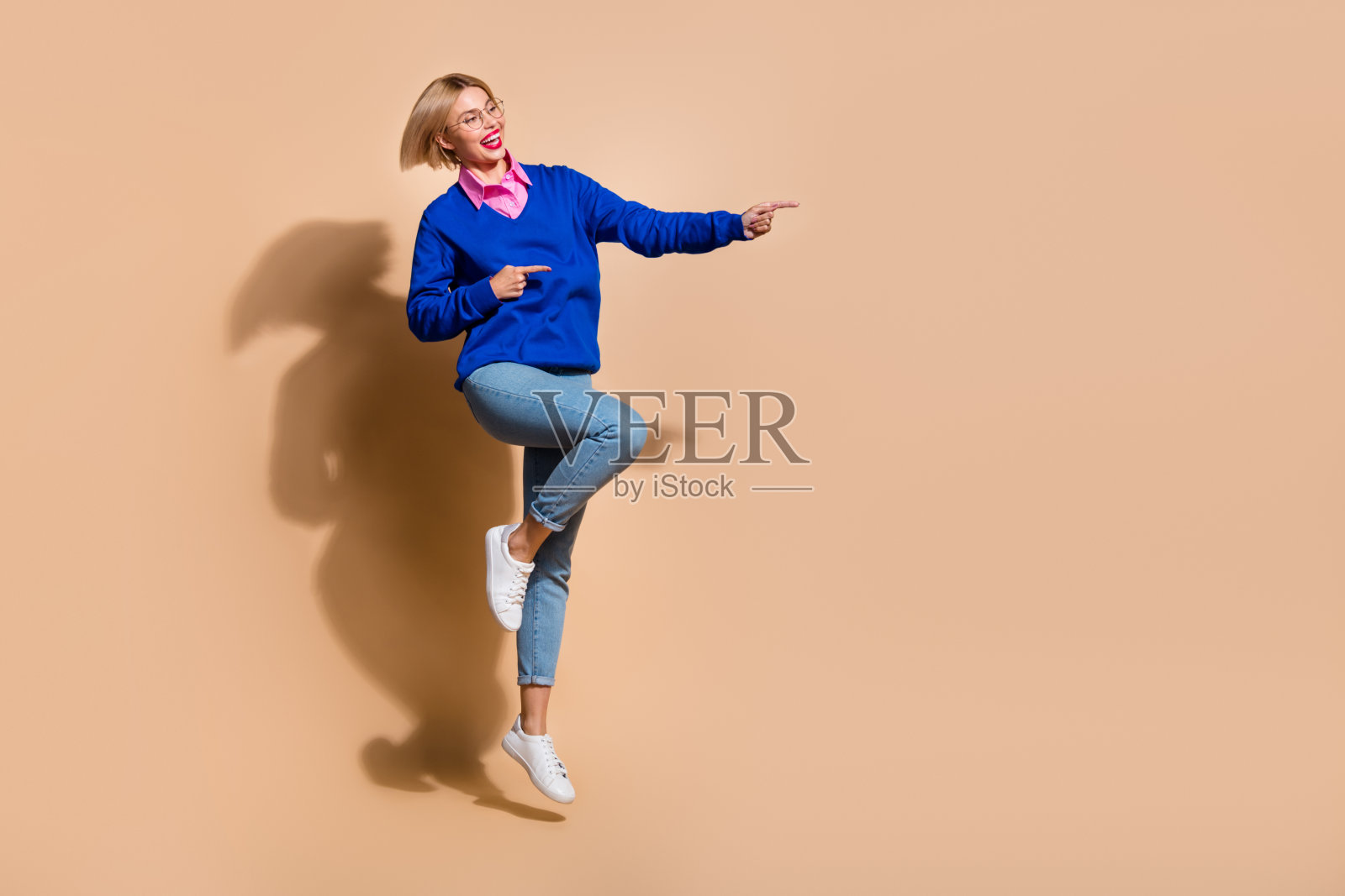 商务女性穿着正装的全身照片，直接指空，新工作场所隔离在米色背景上照片摄影图片