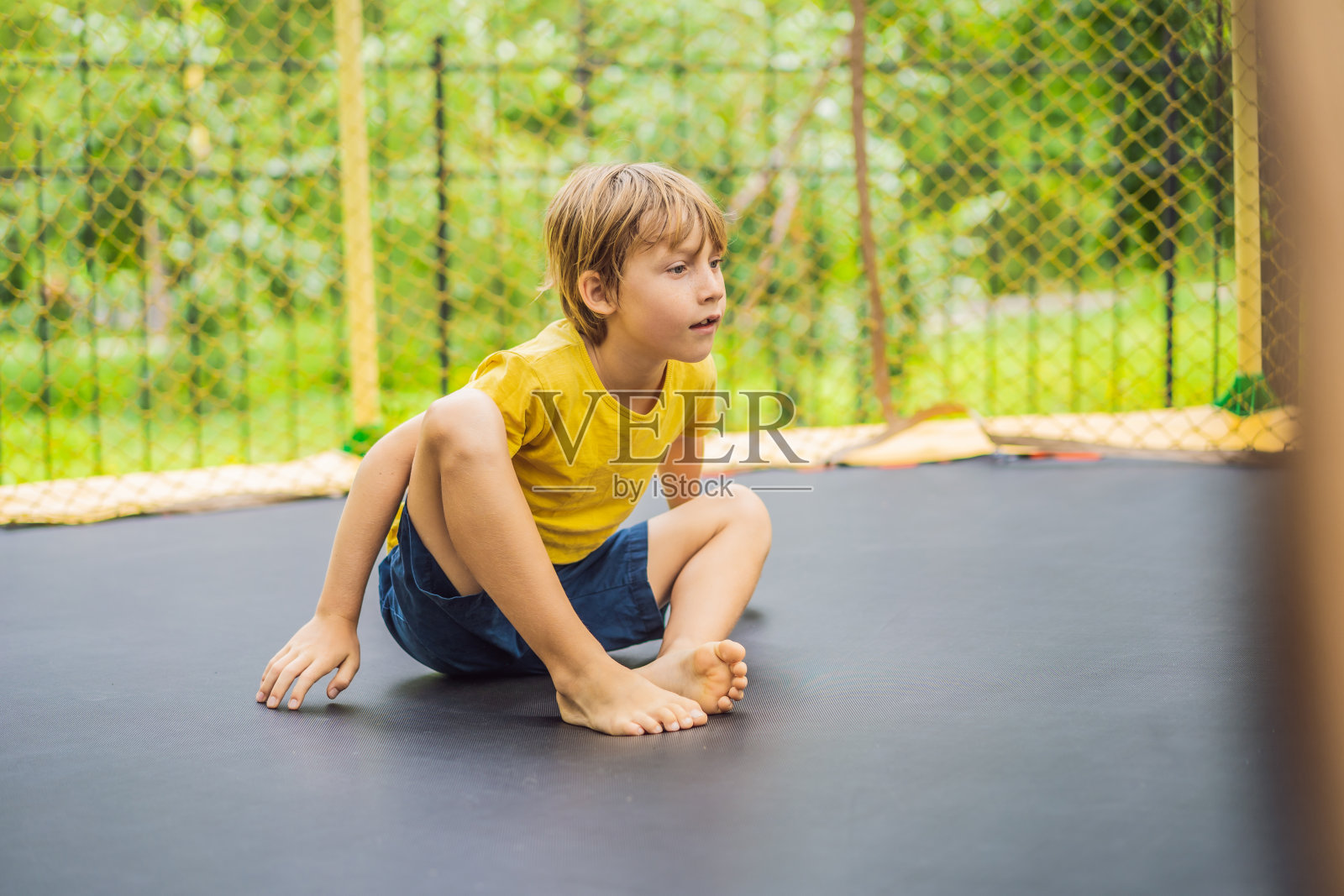 快乐的男孩在户外花园的蹦床上跳向天空照片摄影图片