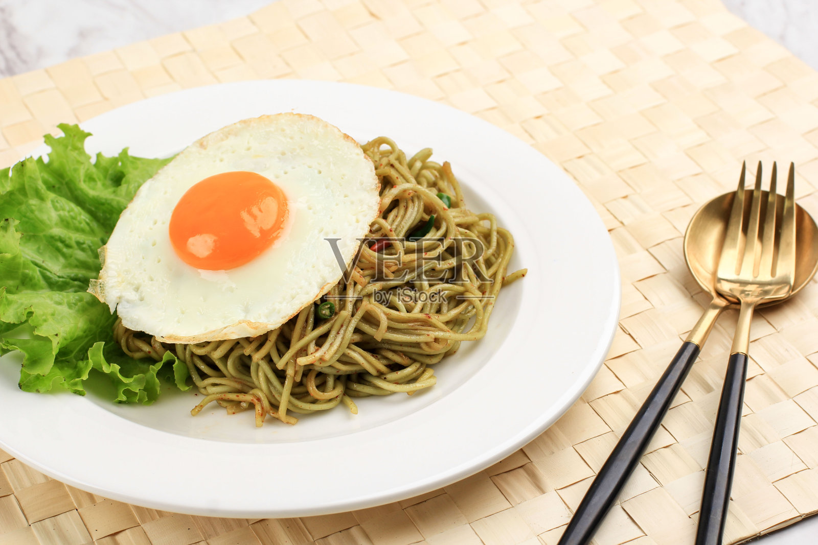 近景:白色陶瓷圆盘上的健康香辣绿鸡蛋生菜方便面。照片摄影图片