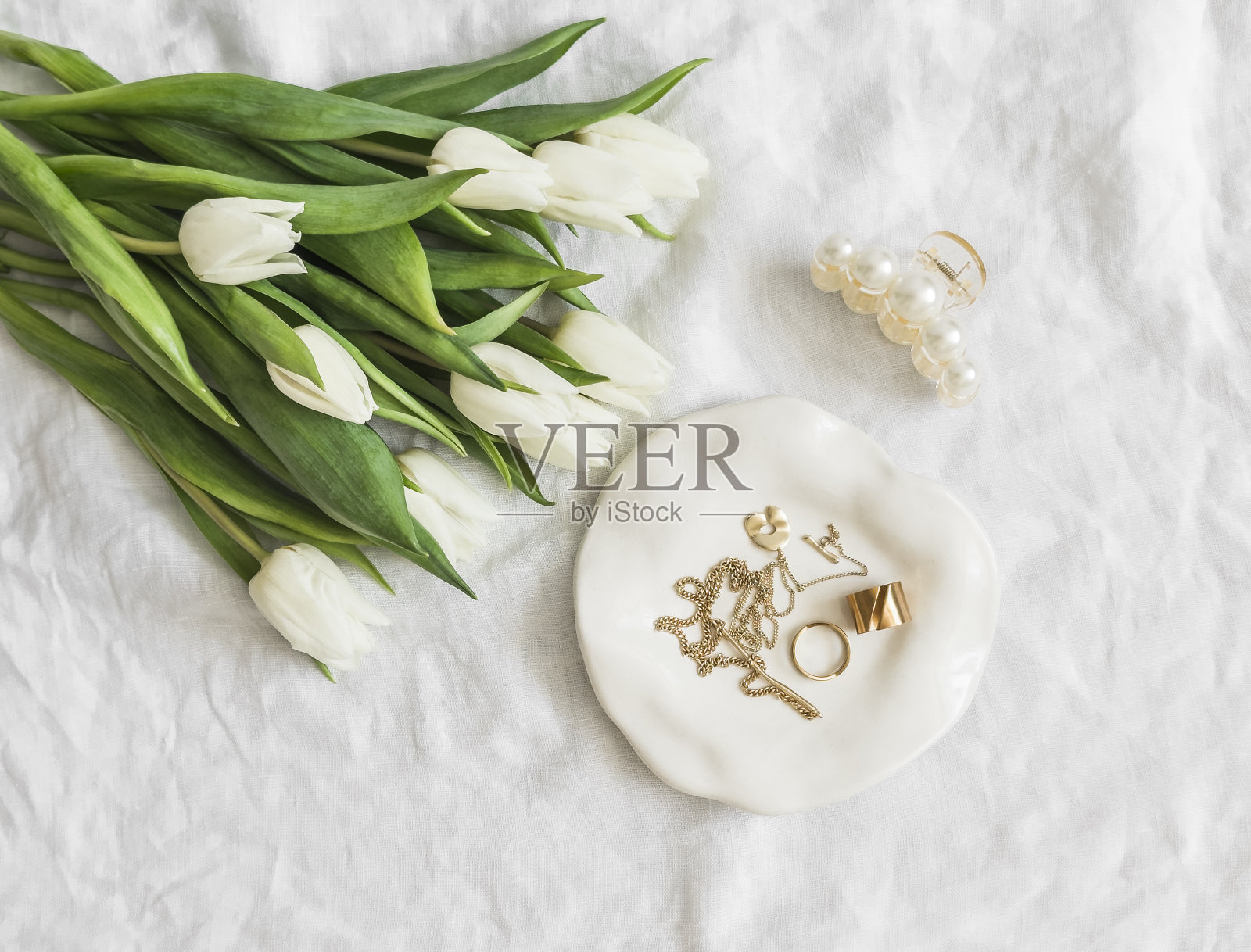 女性的背景。服装首饰，一束郁金香，一个发夹-审美美容配件上的浅色背景，俯视图照片摄影图片