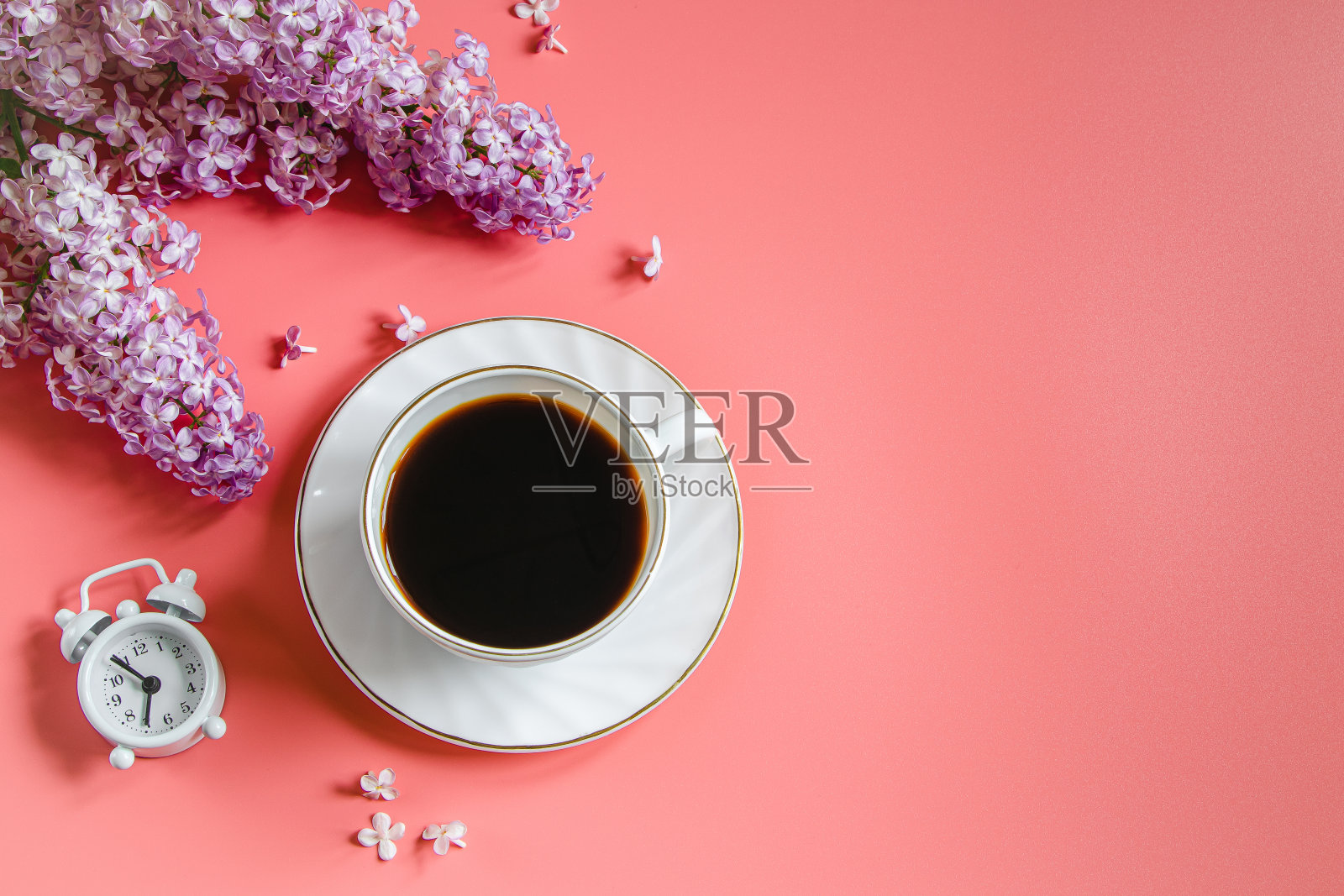 闹钟，紫丁香花和一杯咖啡在浅色背景。照片摄影图片