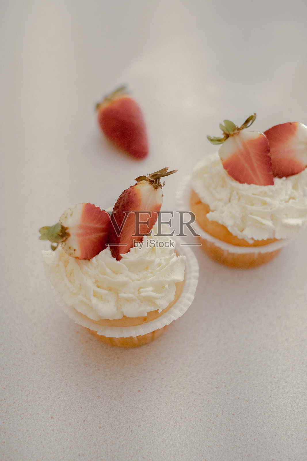 桌子上放着装饰着草莓的纸杯蛋糕，展示着自制的烘焙食品。探索家庭烘焙和小型企业的魅力与这一形象的美味的对待照片摄影图片