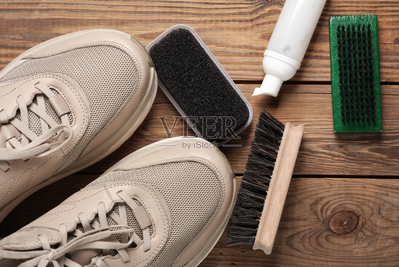 运动鞋用刷子和泡沫喷雾瓶喷在木板上。鞋护理照片摄影图片