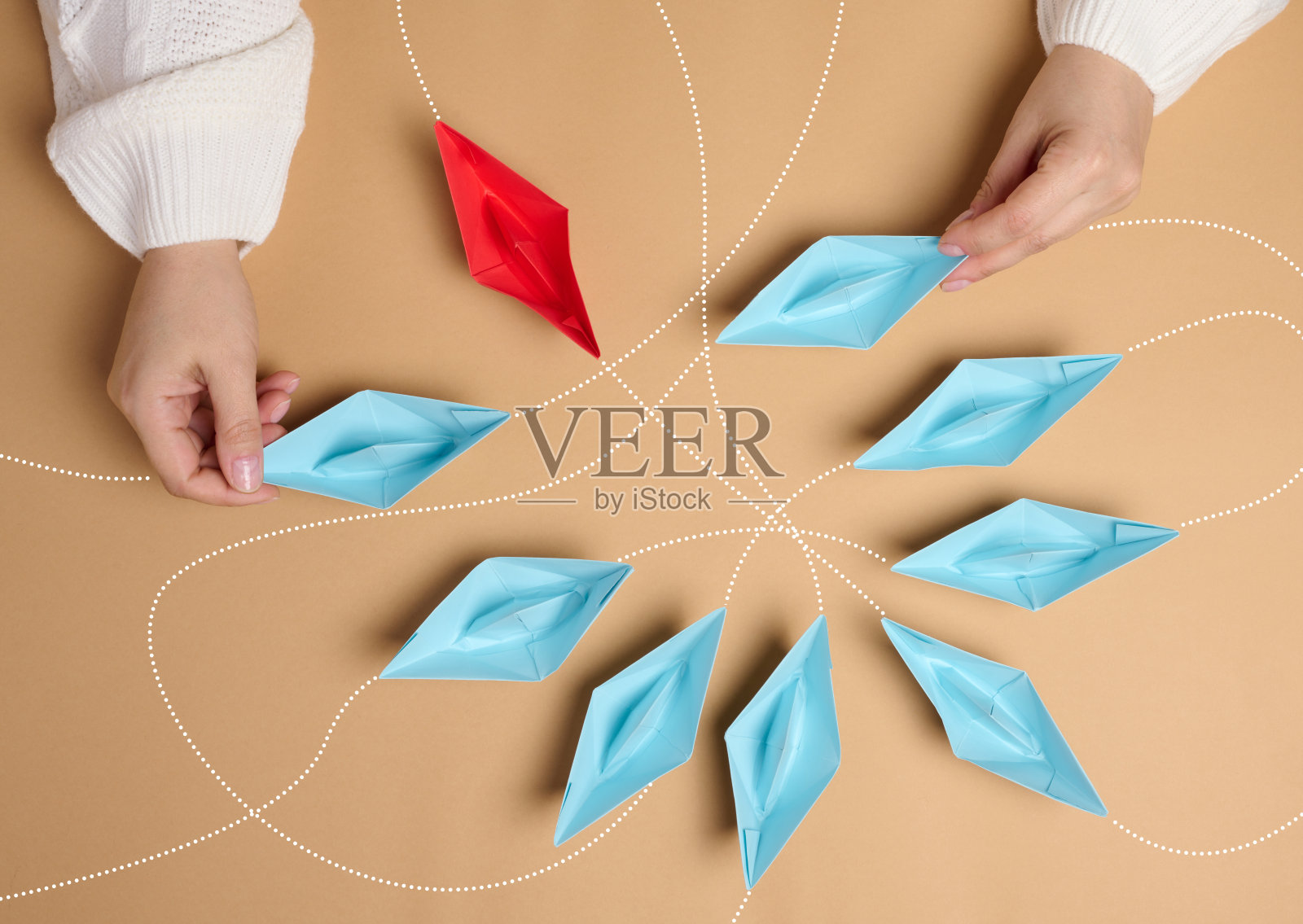 一个女人手里的纸船在棕色背景上有不同的轨迹照片摄影图片