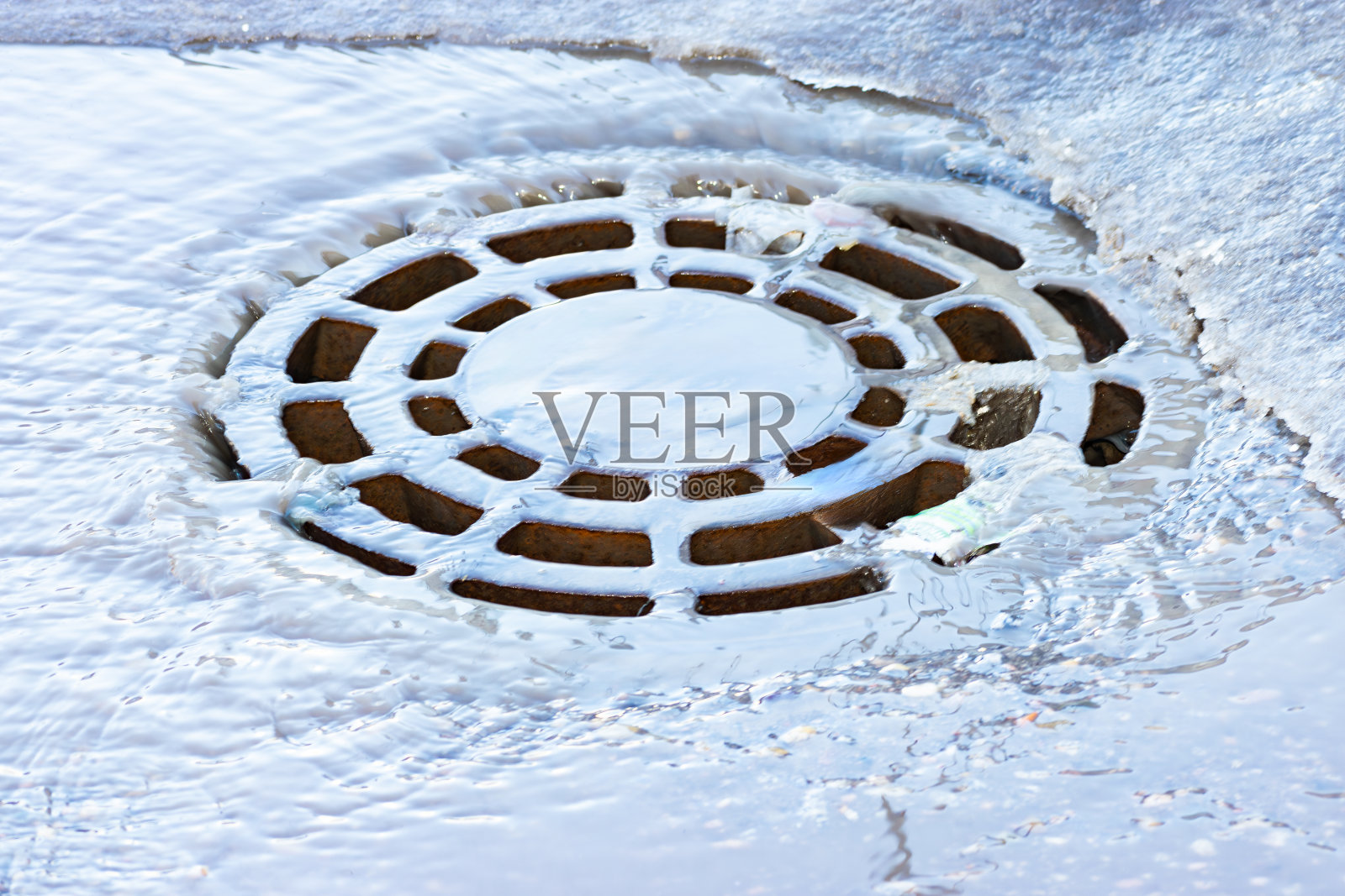 冰雪融化的水流入雨排水井口照片摄影图片