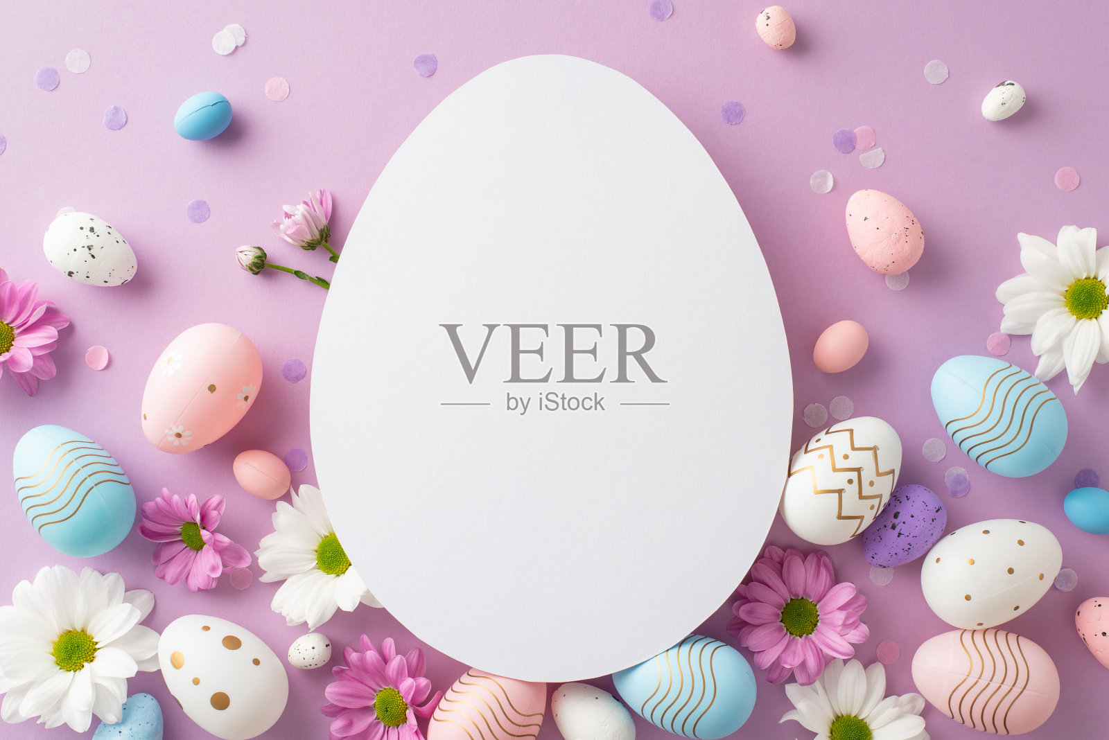 时尚的复活节设置照片。鸟瞰图是鸡蛋、活泼的菊花和淡紫色背景上的五彩纸屑，上面有一个空的蛋形区域，可以放文字或广告照片摄影图片