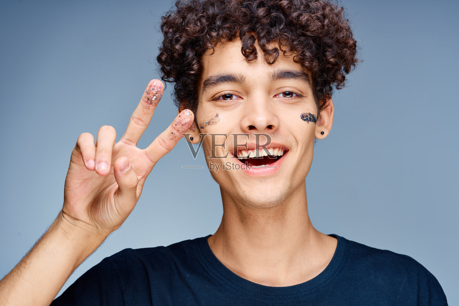 一头卷发的帅哥在脸上敷黑色面膜美容照片摄影图片