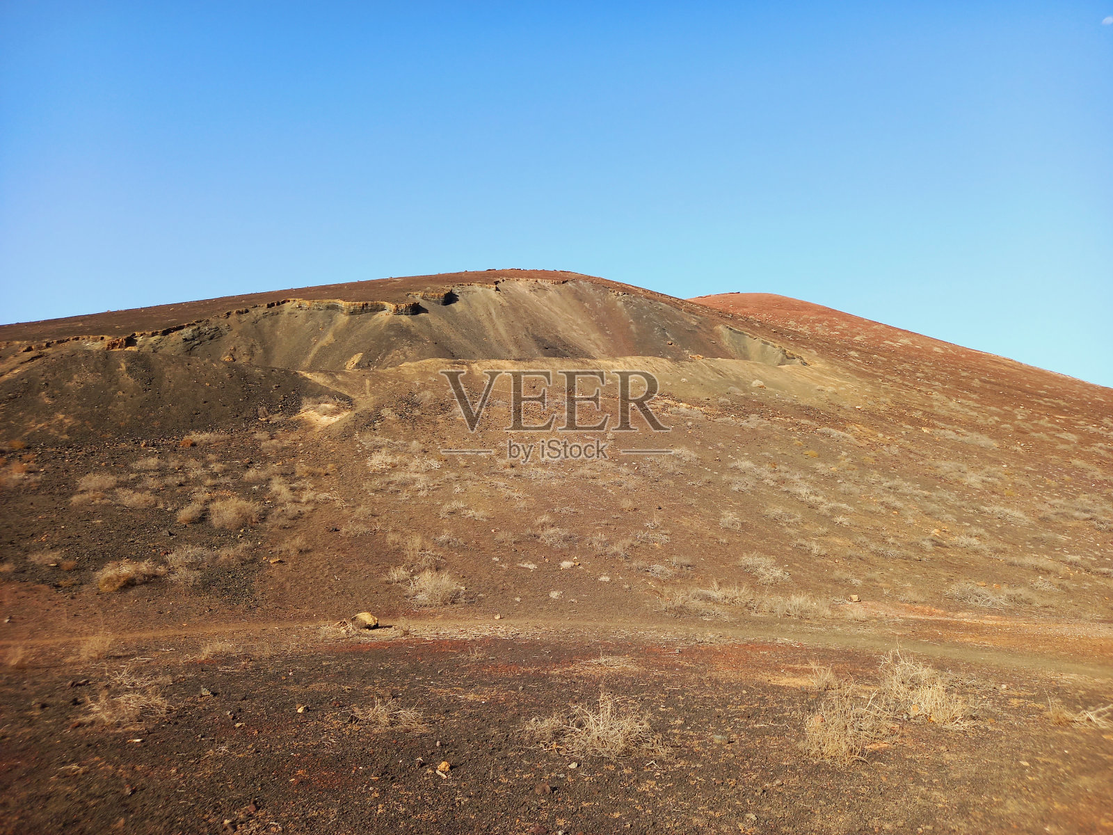蓝天下沙漠地区的火山口和休眠火山的斜坡。风景和极端的自然。照片摄影图片