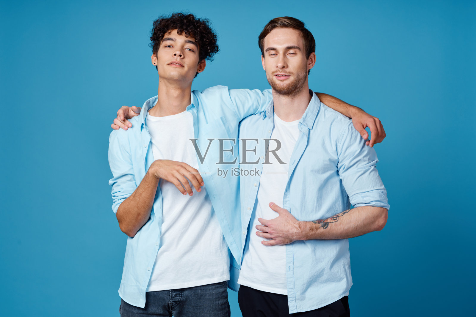 朋友们拥抱在蓝色背景有趣匹配衬衫白色t恤裤子照片摄影图片