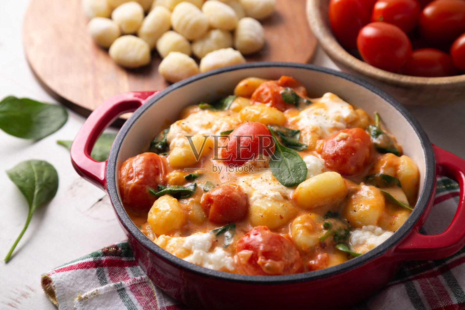 近距离的砂锅汤圆在奶油番茄酱与小菠菜和融化的马苏里拉奶酪照片摄影图片